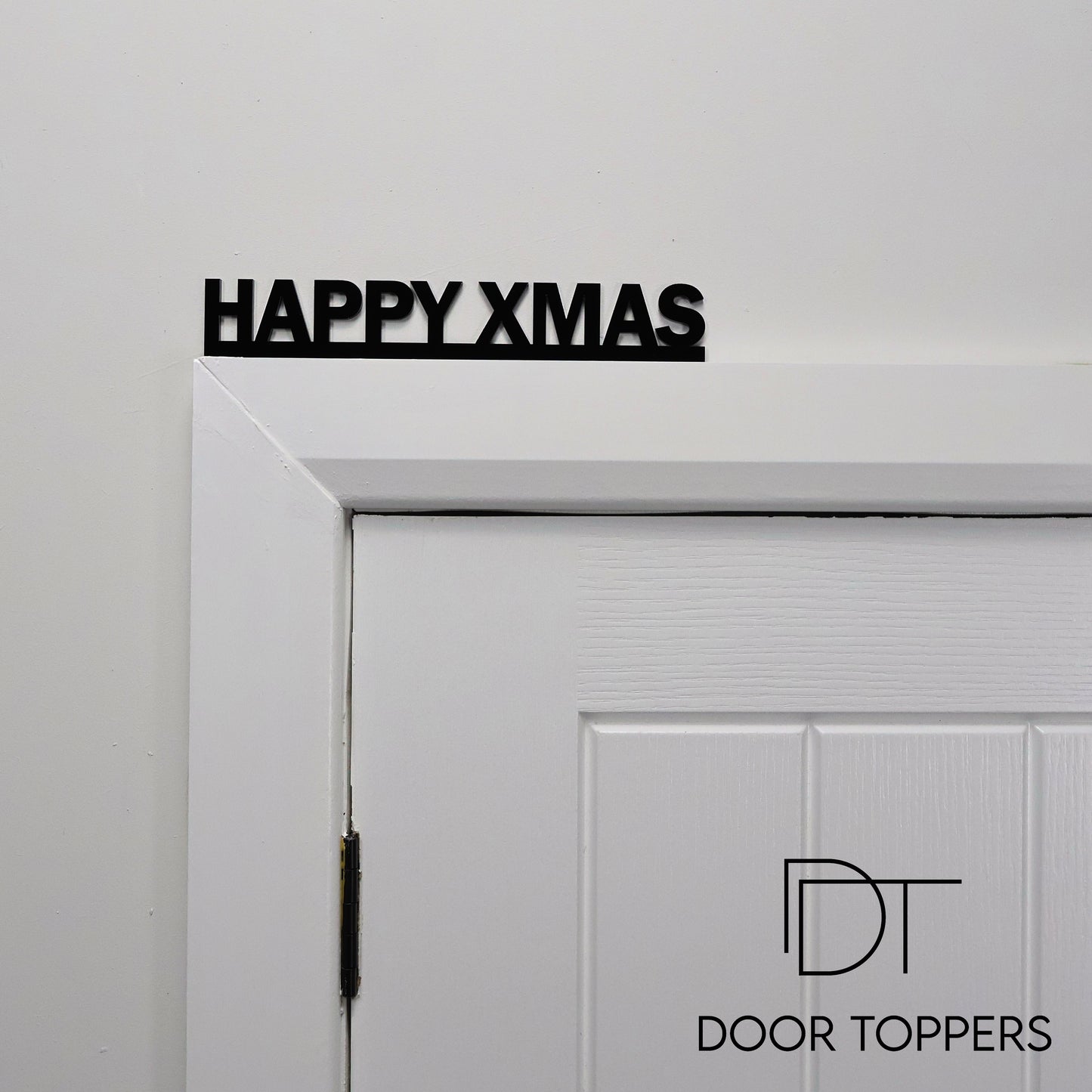HAPPY XMAS acrylic sign displayed above a door, a modern Christmas decoration handmade in the UK.