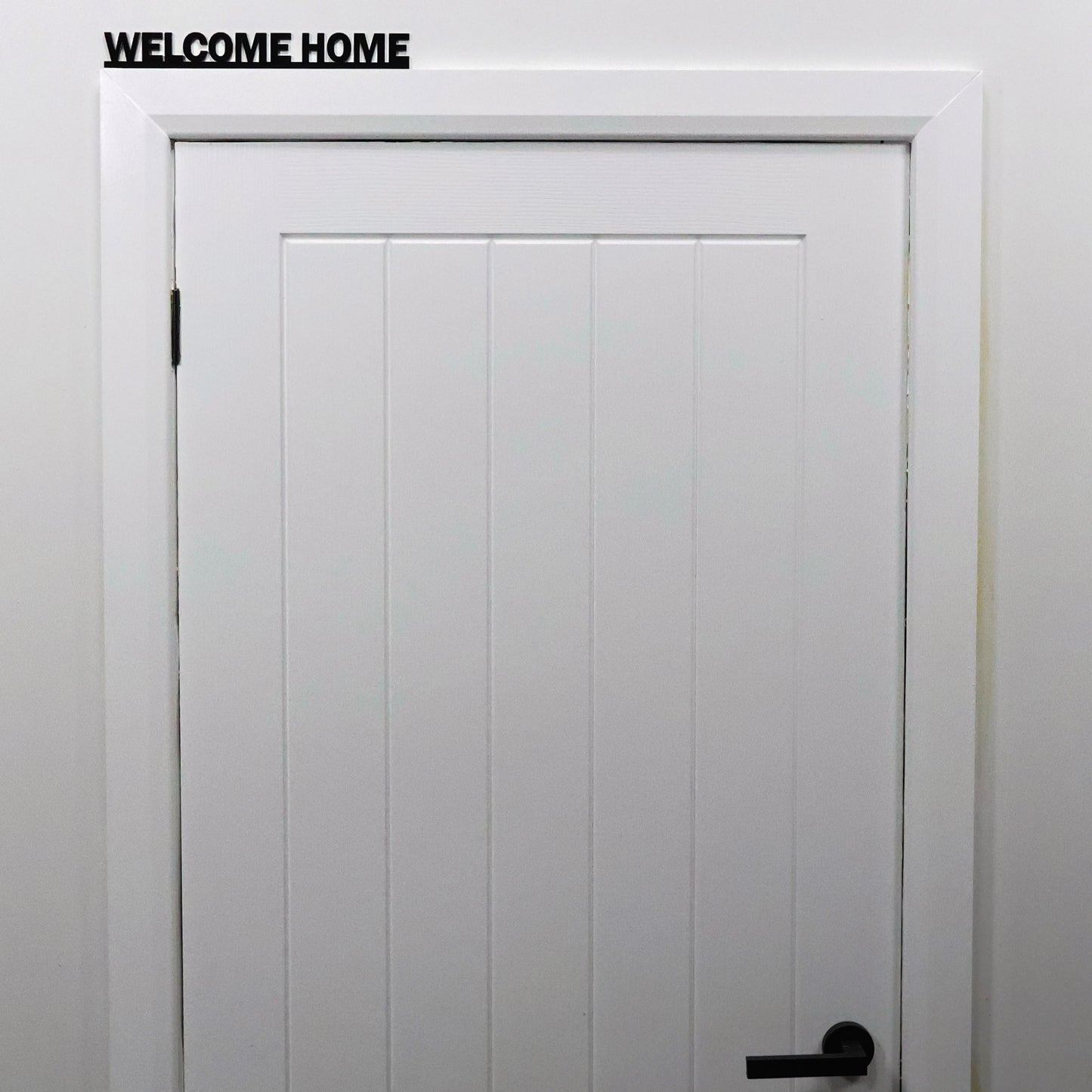 Black acrylic WELCOME HOME sign shown on mantel in cosy living room