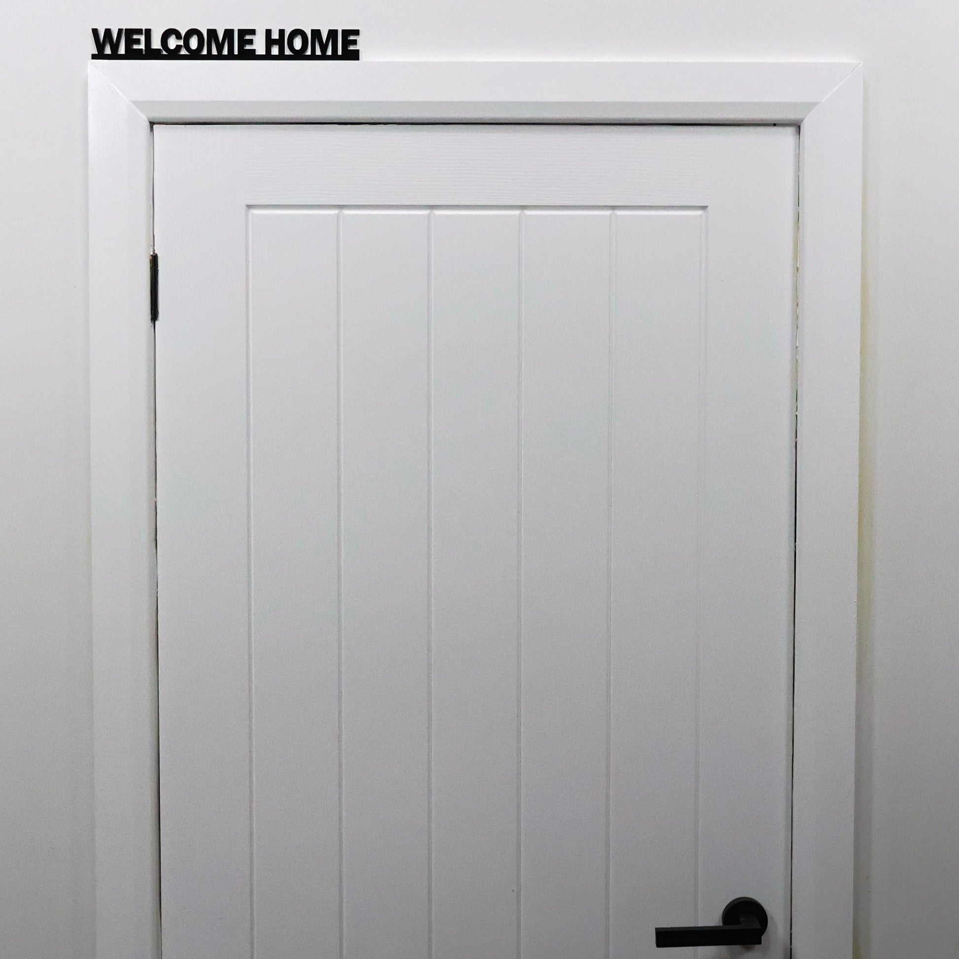 Black acrylic WELCOME HOME sign shown on mantel in cosy living room