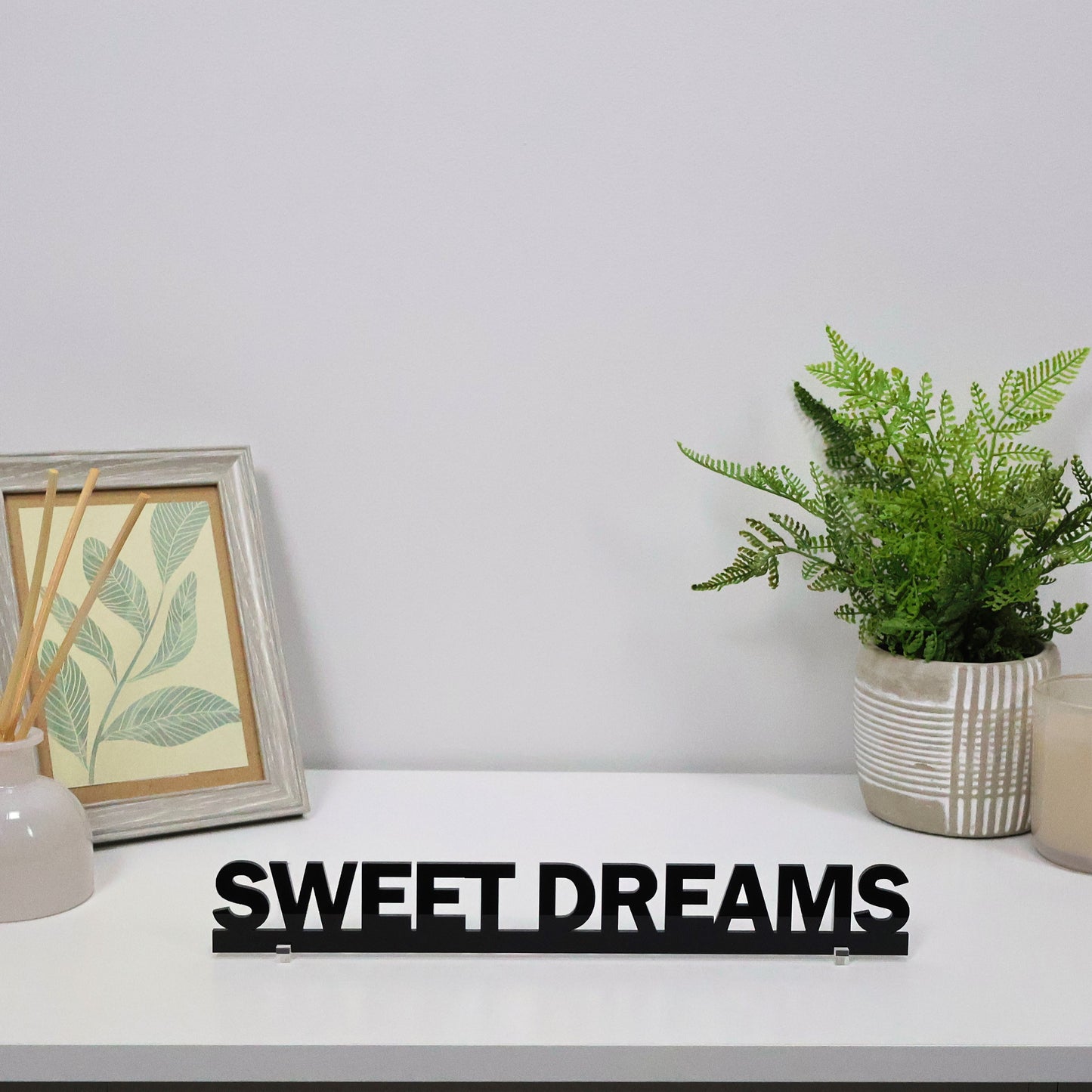 SWEET DREAMS sign shown freestanding on a bedside table beside a lamp