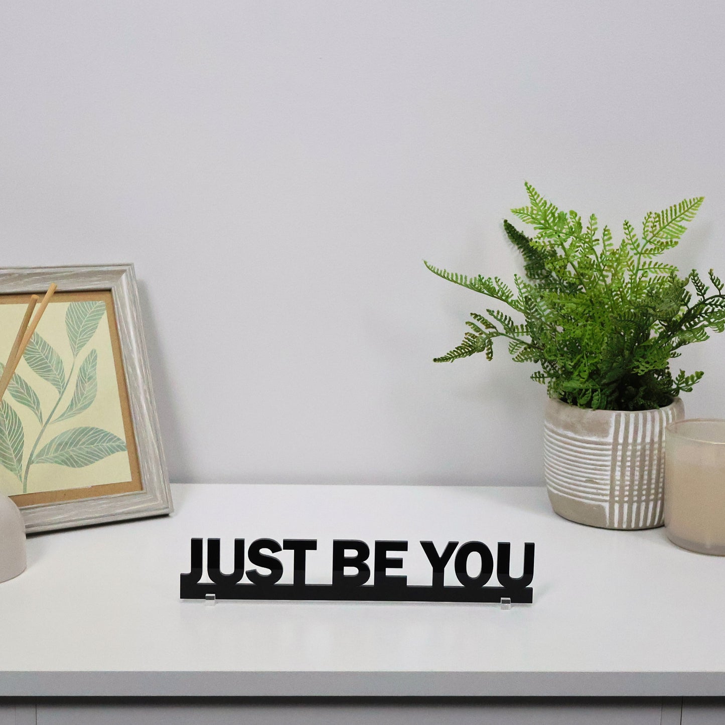 JUST BE YOU sign shown freestanding on a shelf beside a plant