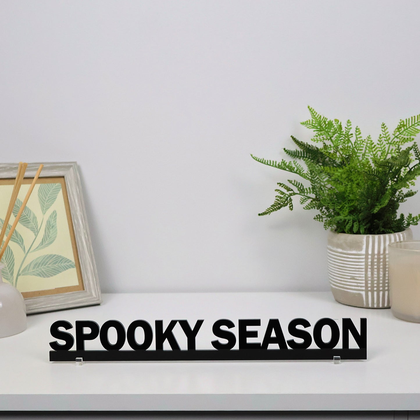 SPOOKY SEASON sign shown freestanding on a mantel beside pumpkins and candles