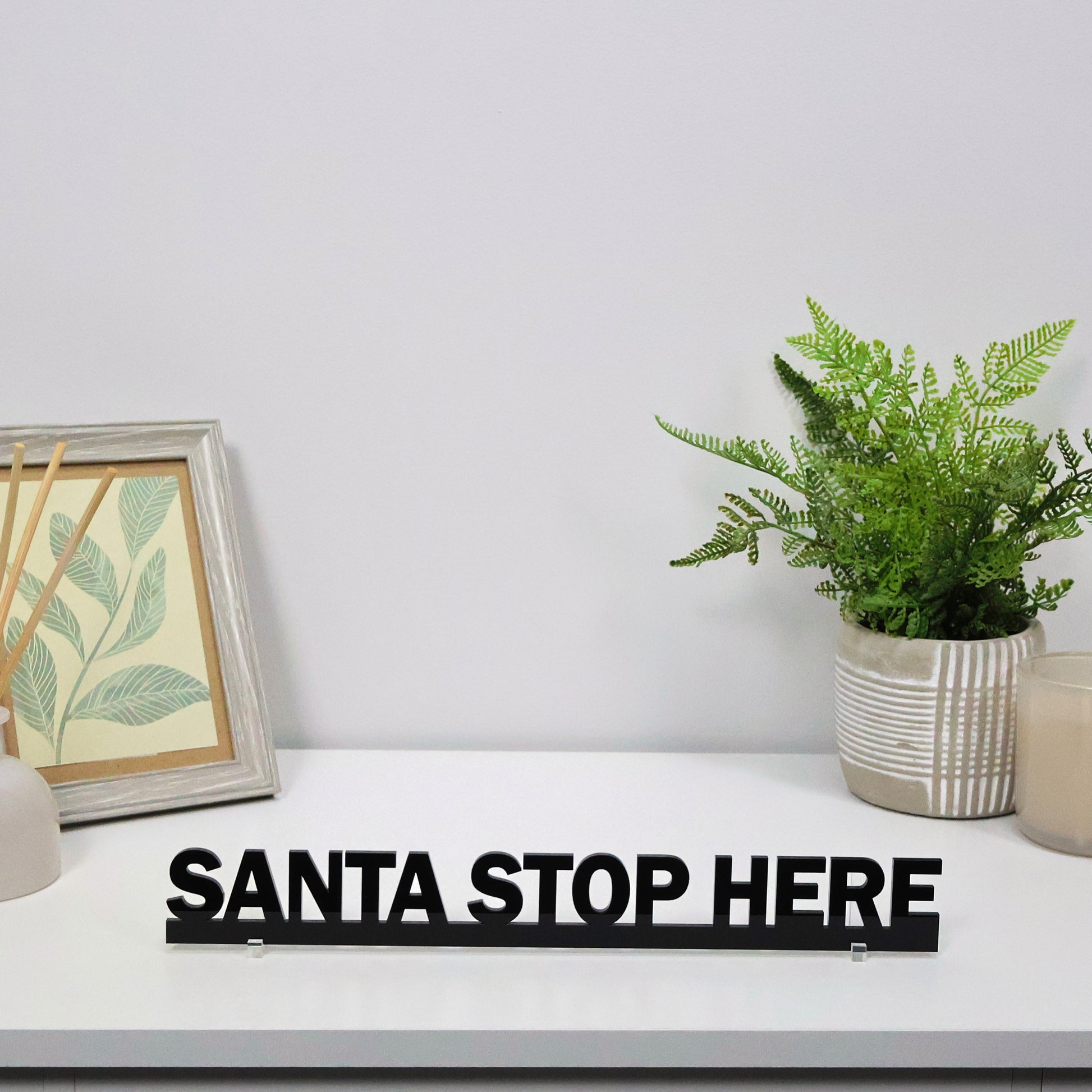 SANTA STOP HERE sign shown freestanding on a mantel beside decorations