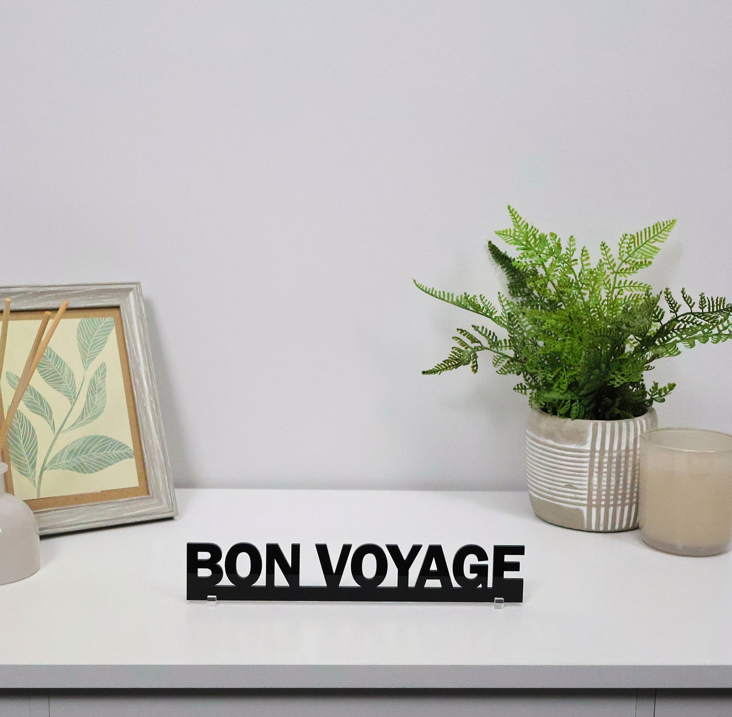 BON VOYAGE sign freestanding on a console shelf beside travel books.