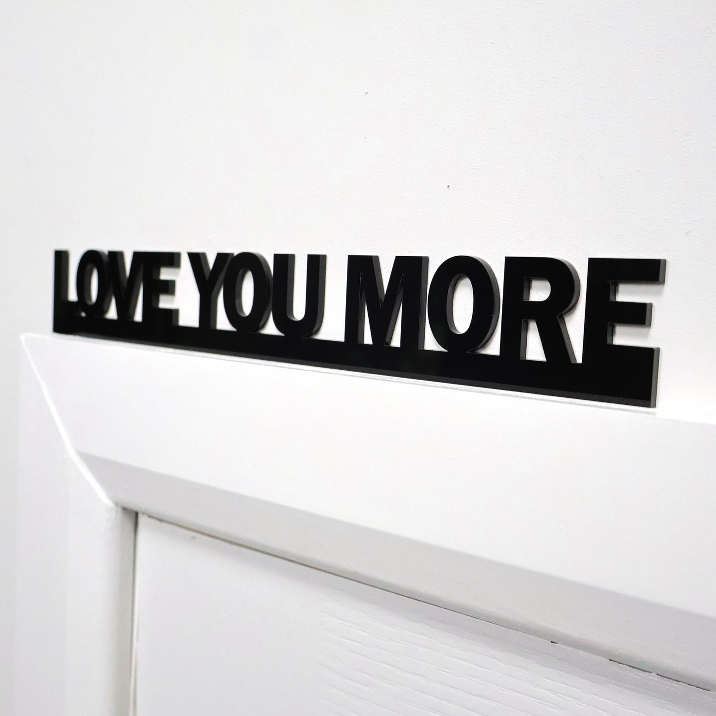 Side angle of the LOVE YOU MORE sign above a door showing fit and thickness
