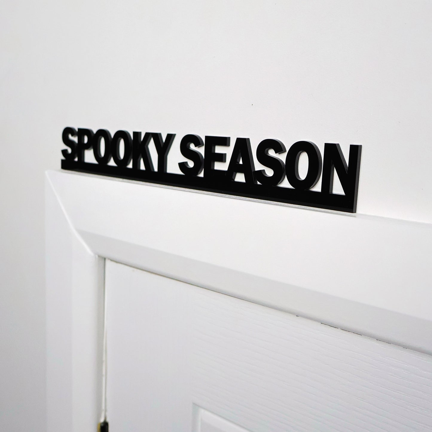 Black acrylic Halloween wall sign displayed above a white door frame