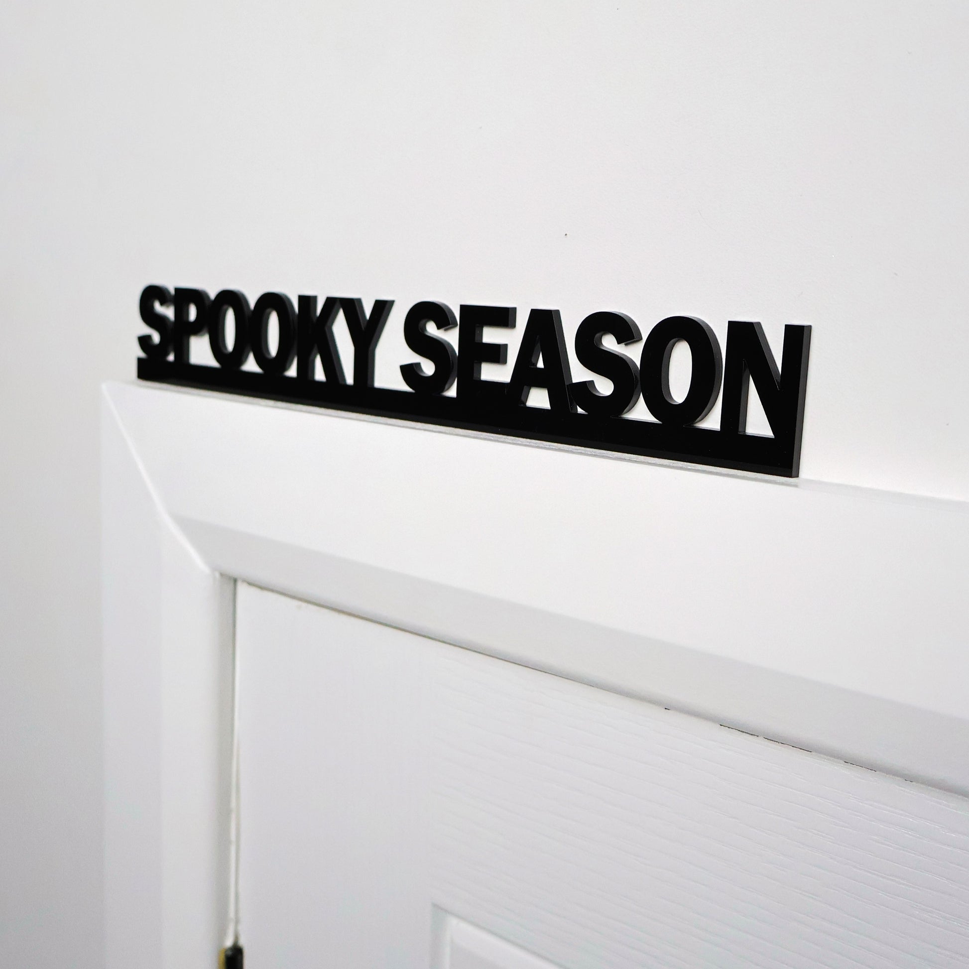 Black acrylic Halloween wall sign displayed above a white door frame