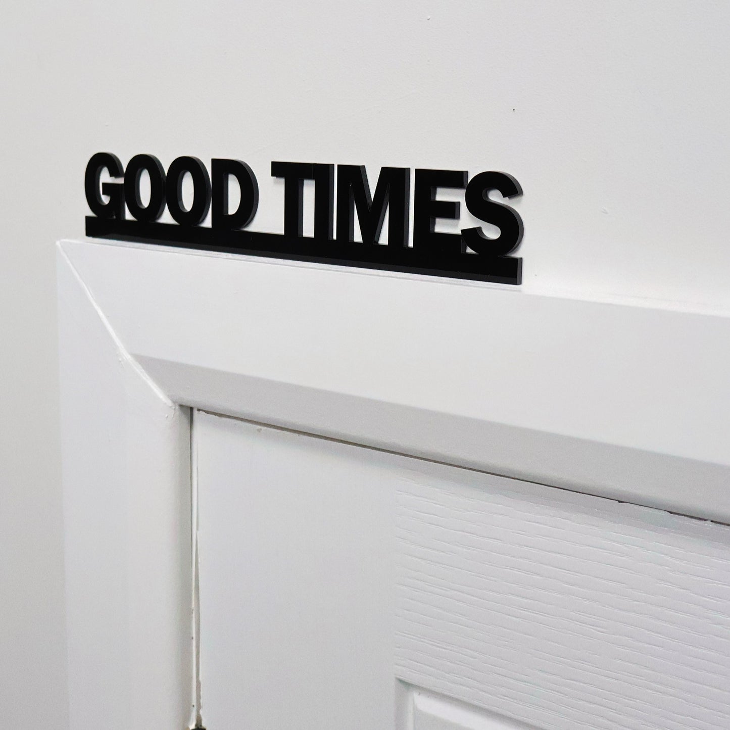 Close-up of GOOD TIMES lettering – glossy black recycled acrylic finish