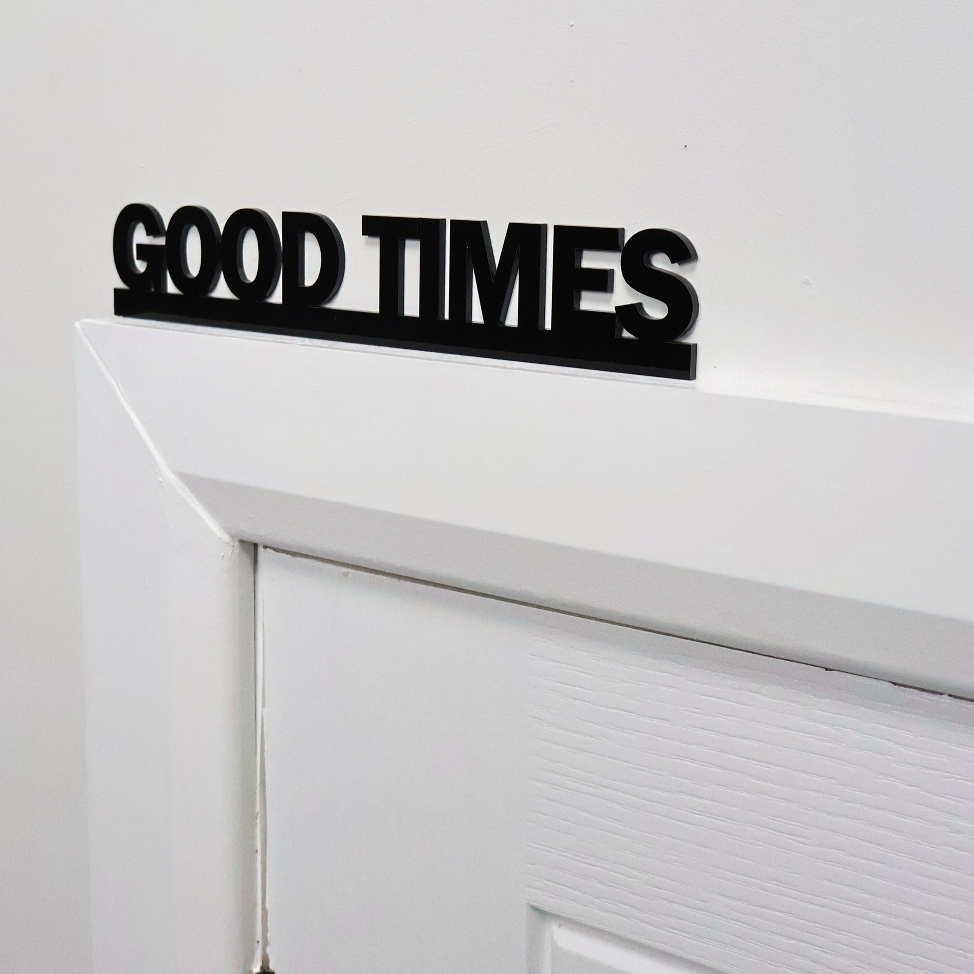 Close-up of GOOD TIMES lettering – glossy black recycled acrylic finish
