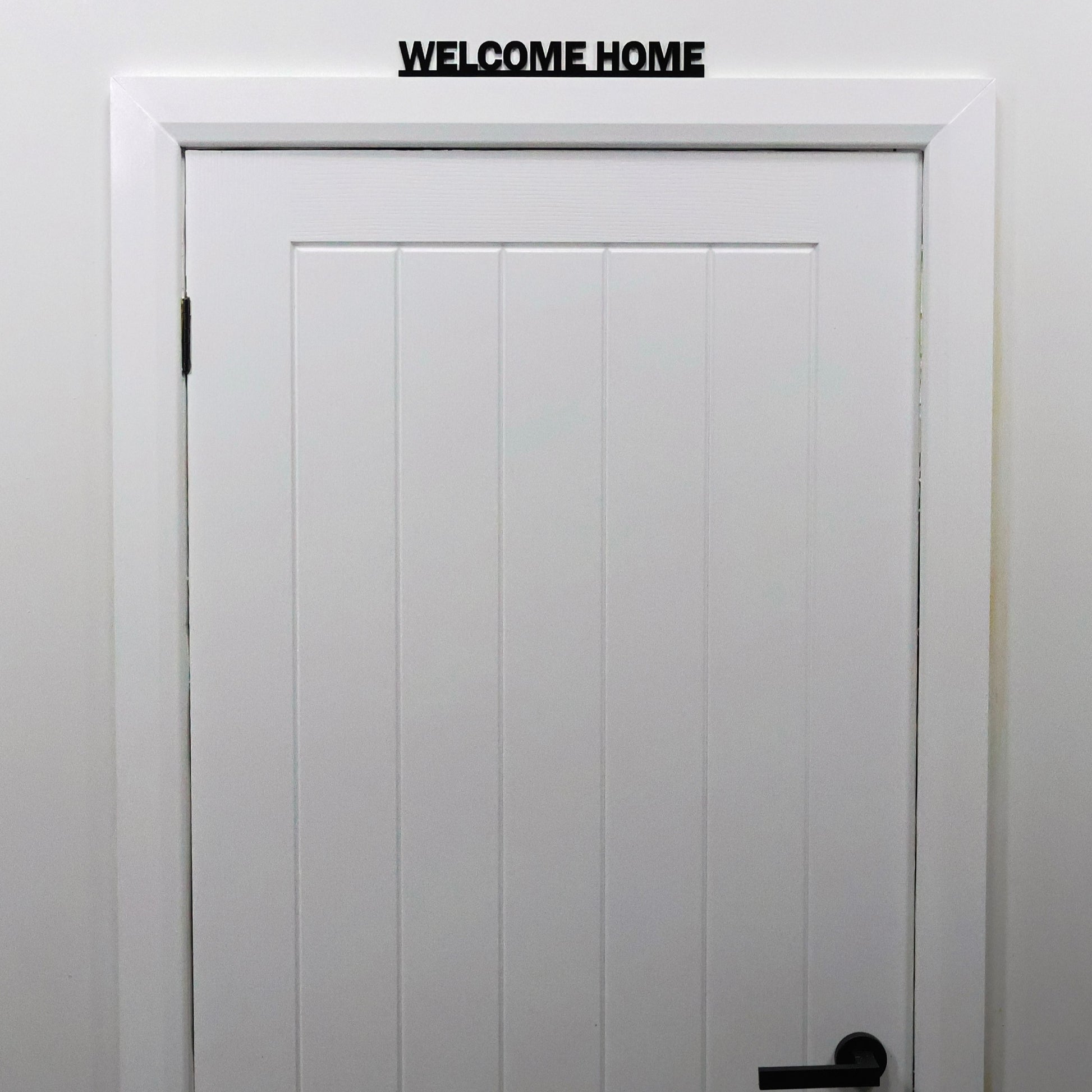 WELCOME HOME acrylic sign displayed above a doorway in modern hallway