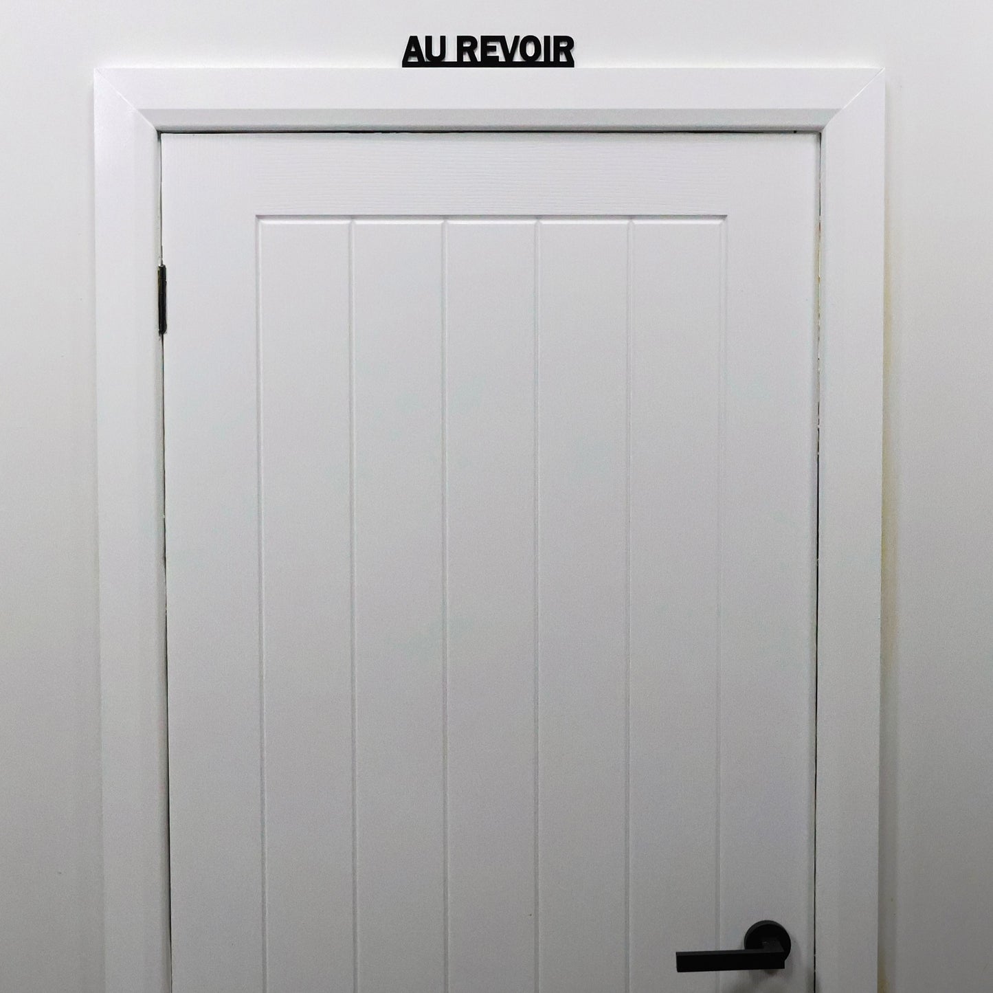 French quote sign shown from a distance on a guest bedroom door frame.