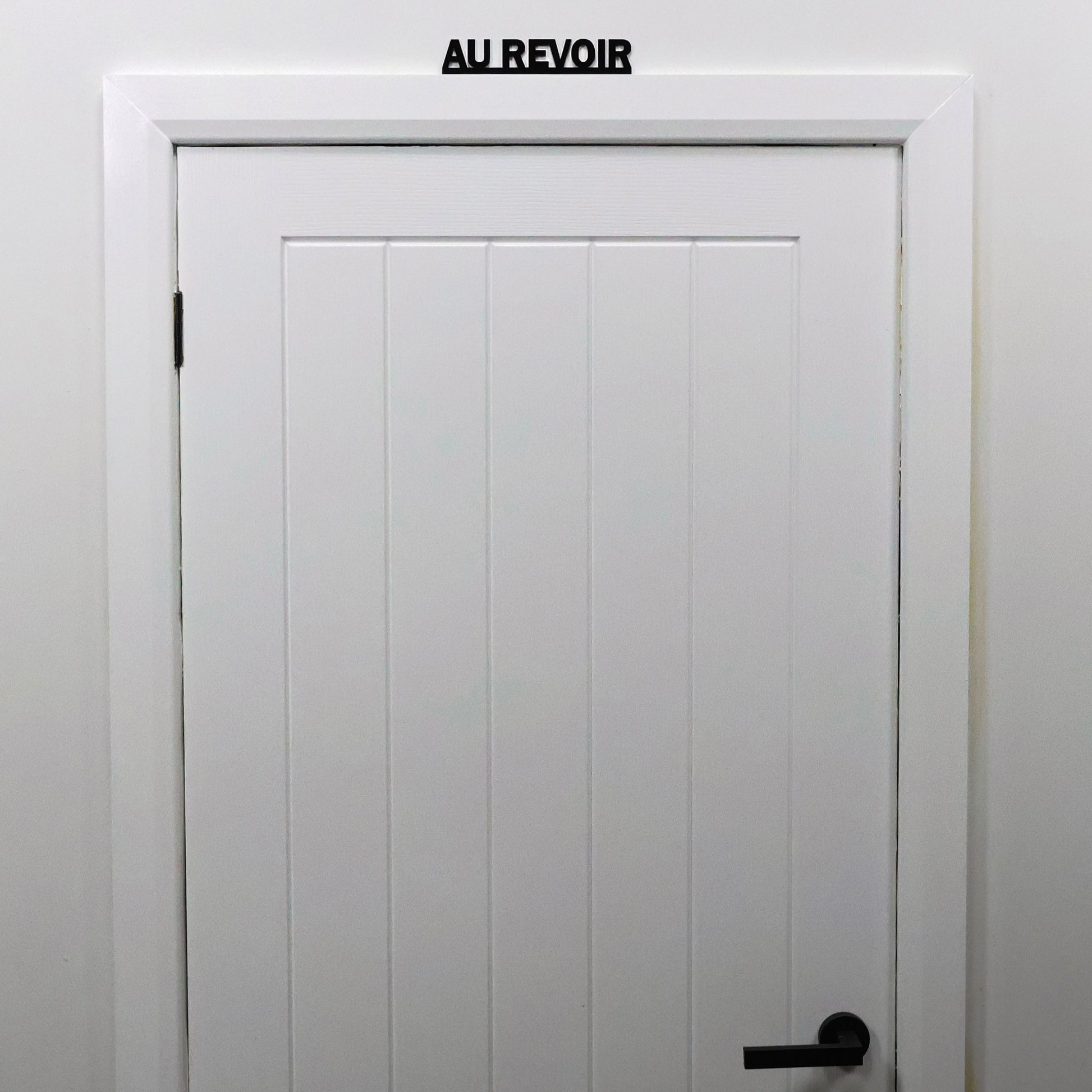 French quote sign shown from a distance on a guest bedroom door frame.