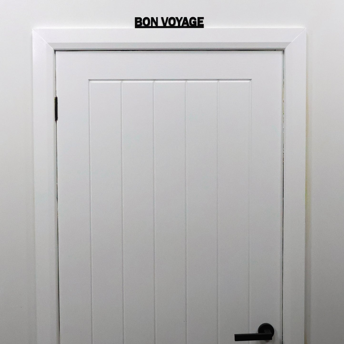 Travel-quote wall sign shown from a distance on a white door frame.