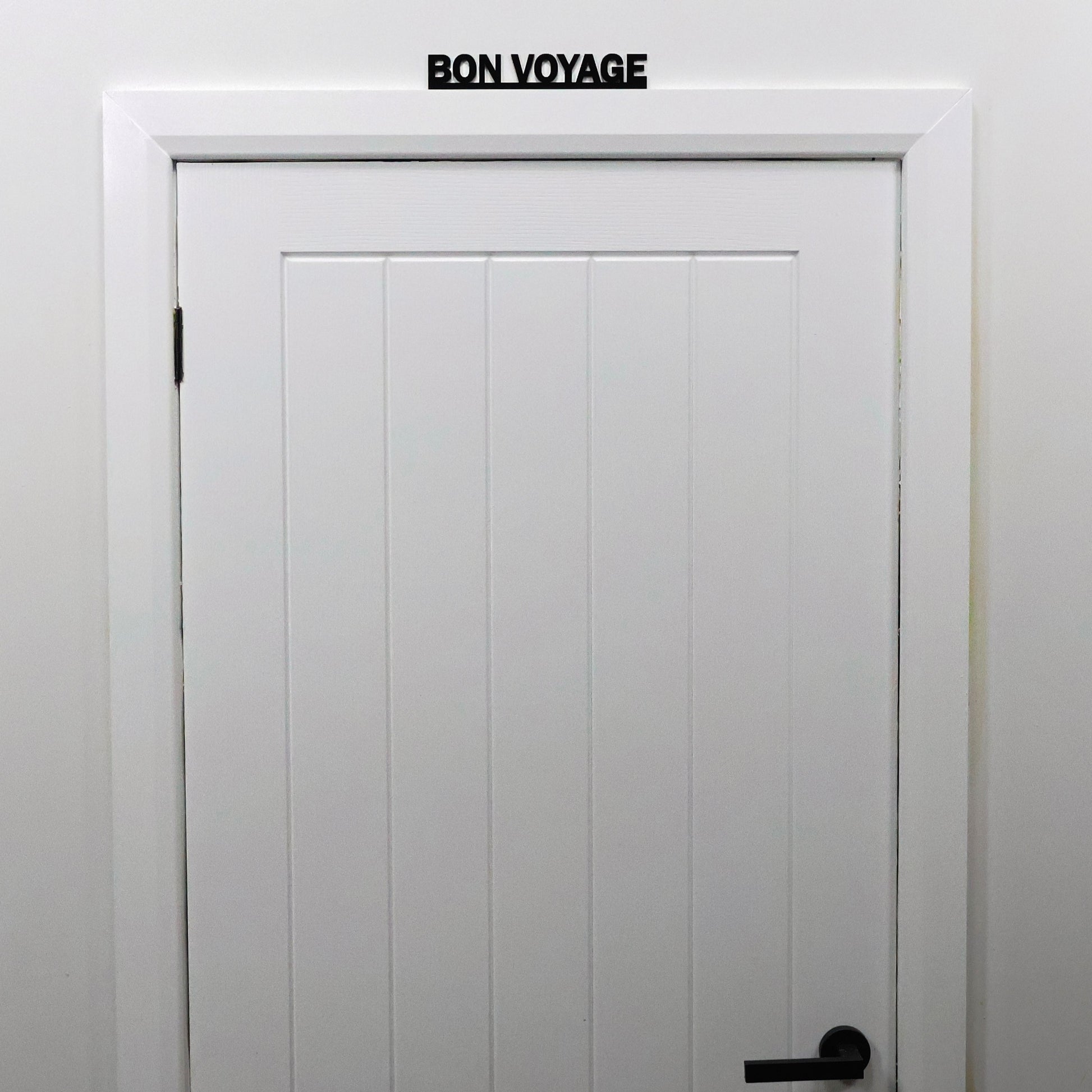 Travel-quote wall sign shown from a distance on a white door frame.