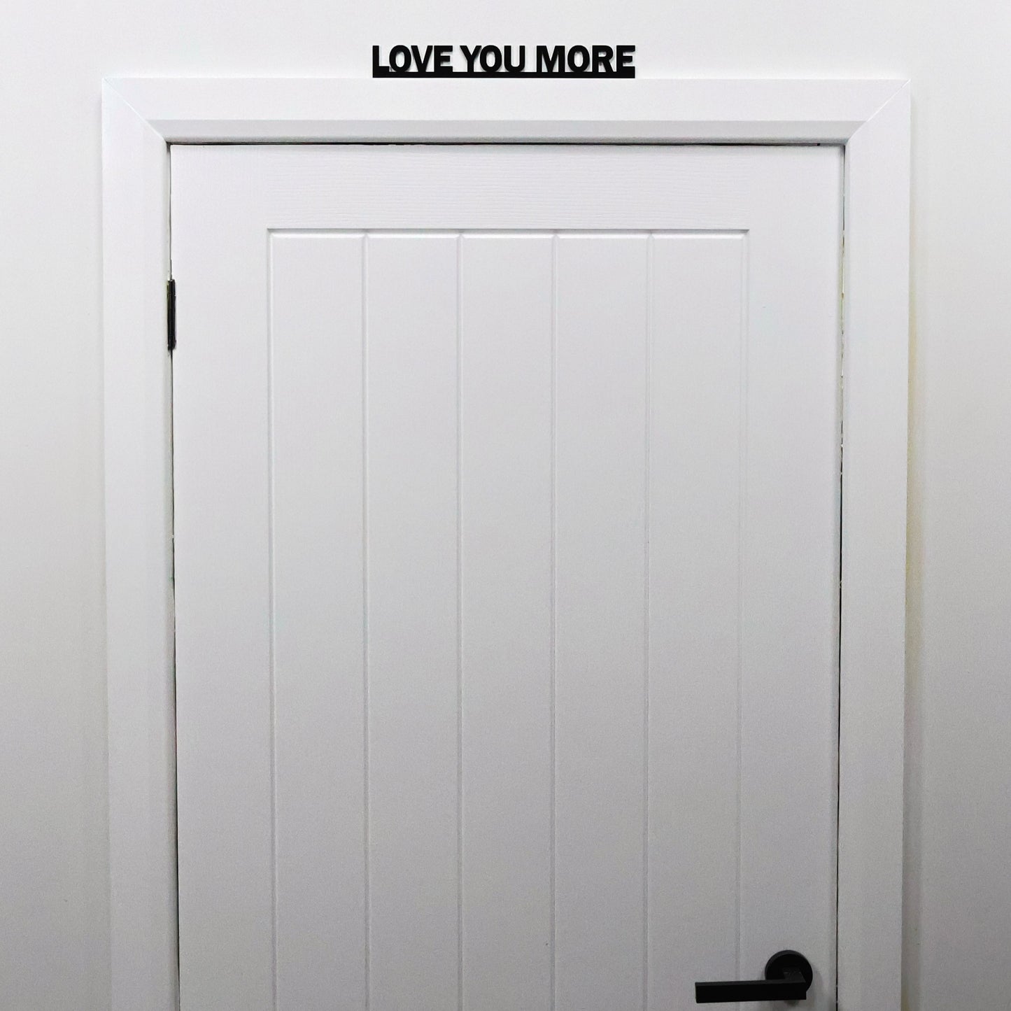 LOVE YOU MORE sign shown from a distance on a door in a bright living space
