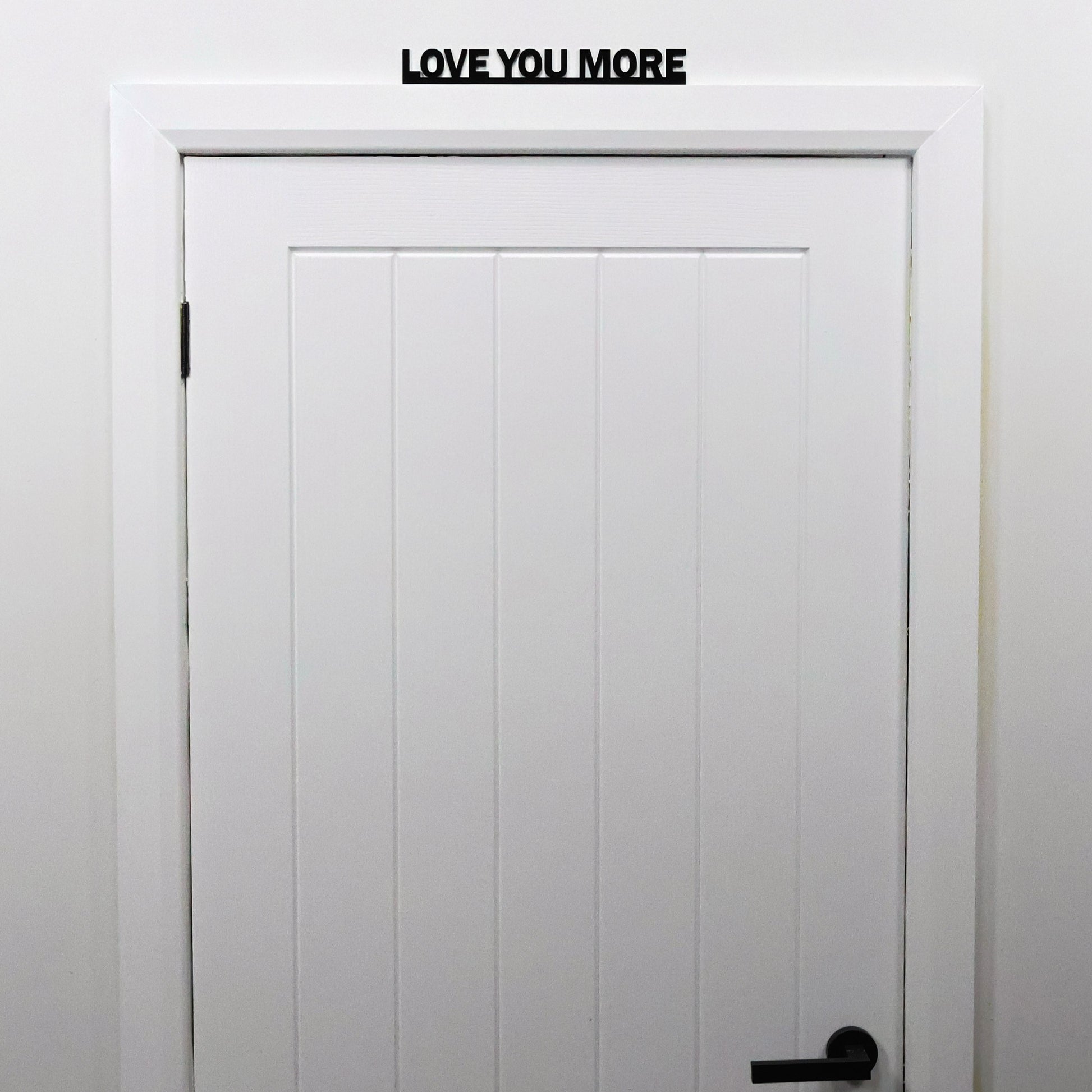 LOVE YOU MORE sign shown from a distance on a door in a bright living space