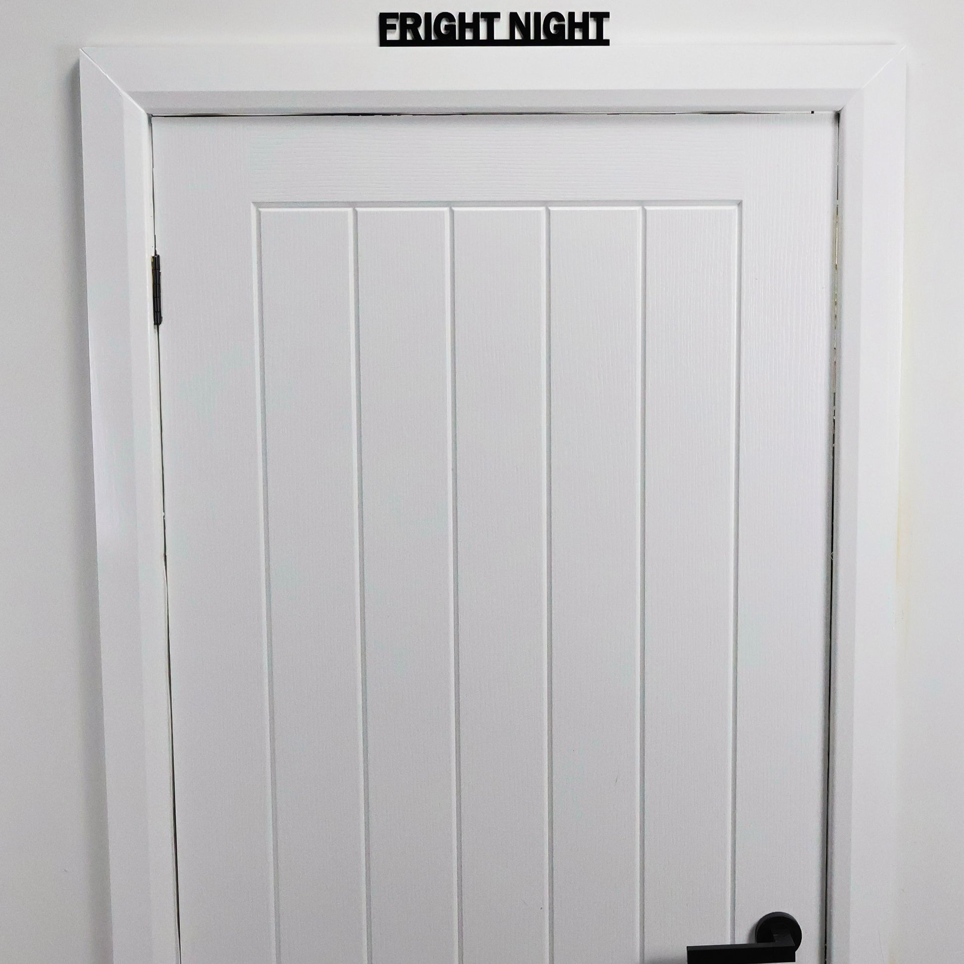 Black acrylic Halloween wall sign displayed above a white door frame