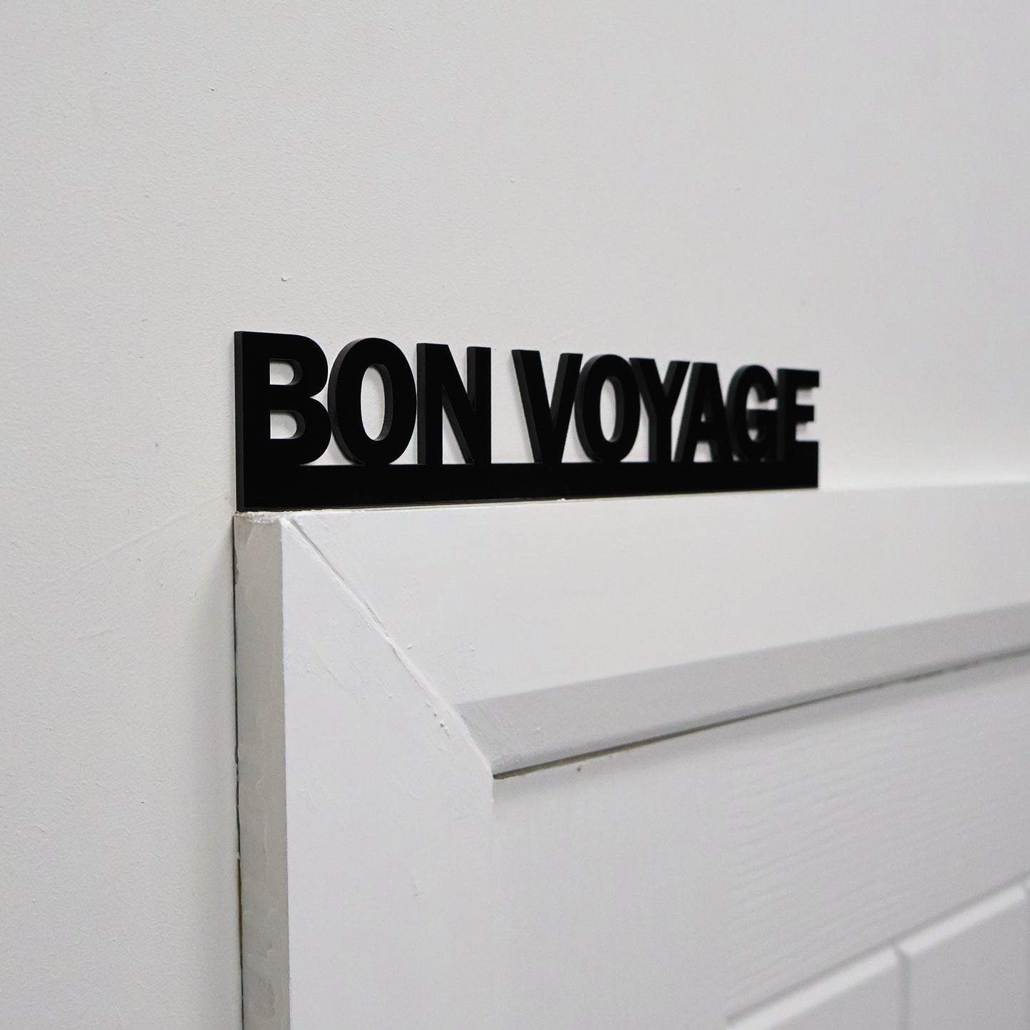 Close-up of glossy lettering on the BON VOYAGE wall sign.