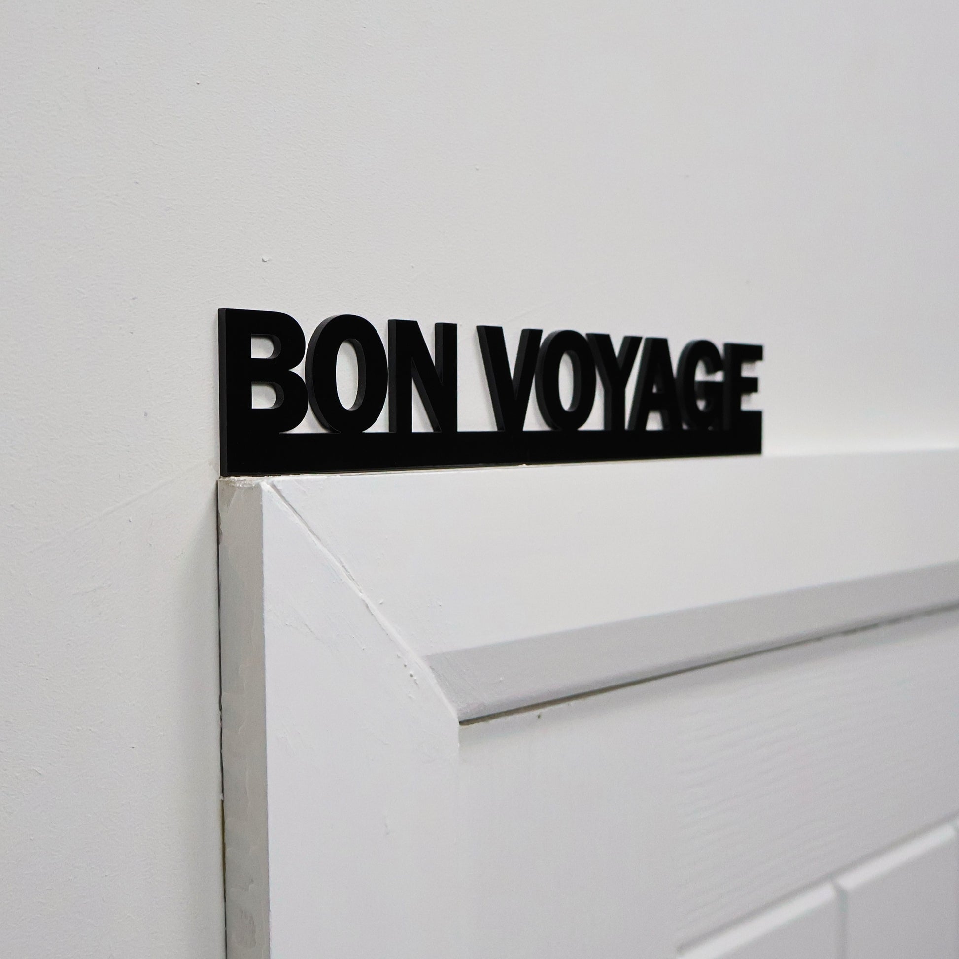 Close-up of glossy lettering on the BON VOYAGE wall sign.