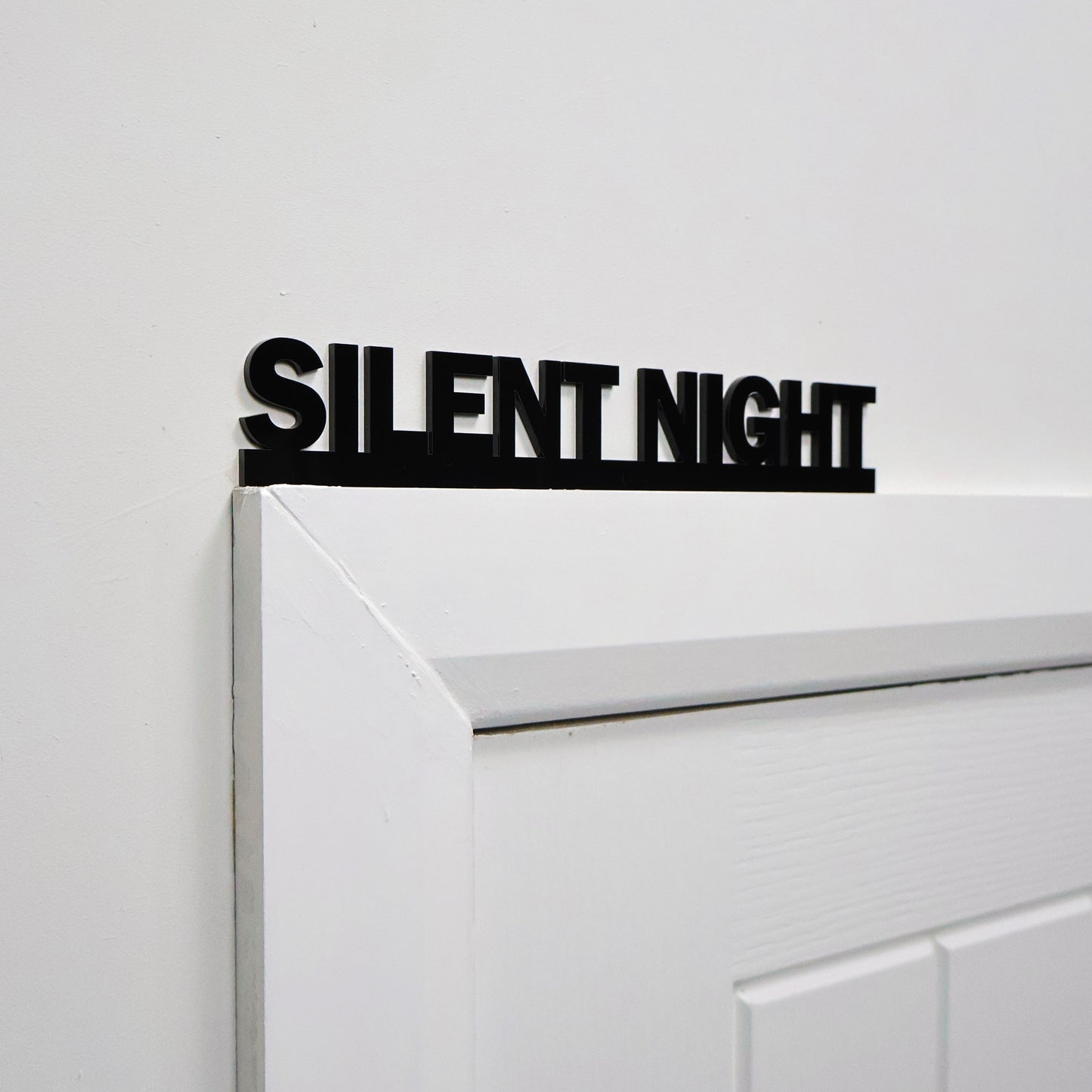 Black acrylic festive wall sign displayed above a white door frame