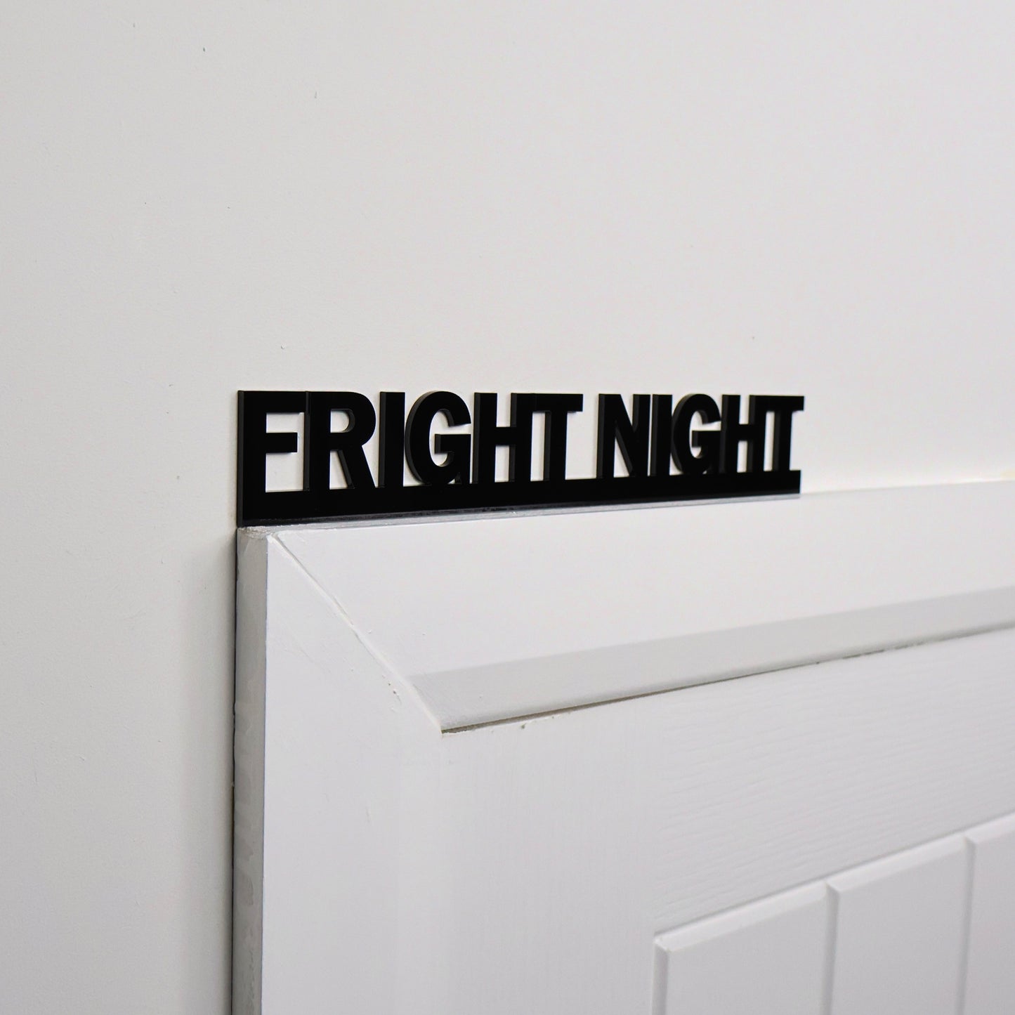 Black acrylic Halloween wall sign displayed above a white door frame
