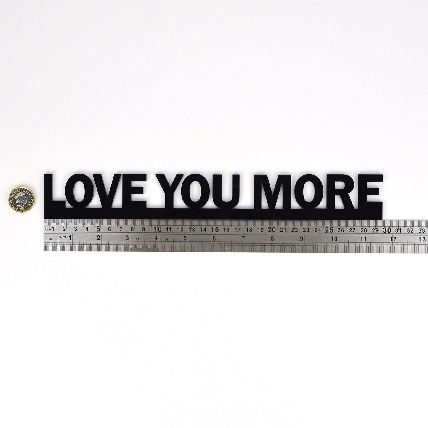 Flat lay showing LOVE YOU MORE Door Topper beside a ruler and pound coin for scale
