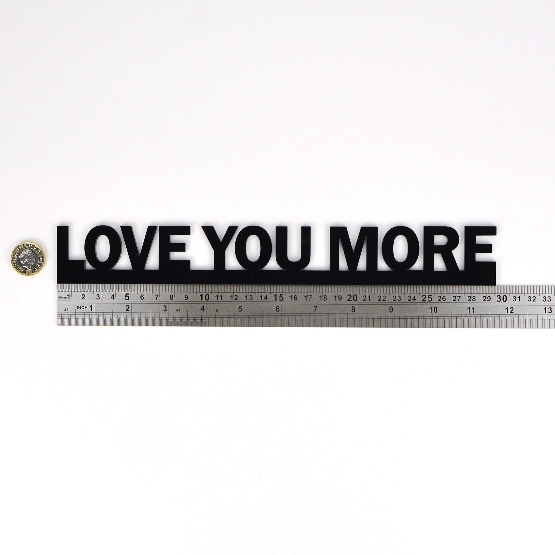 Flat lay showing LOVE YOU MORE Door Topper beside a ruler and pound coin for scale