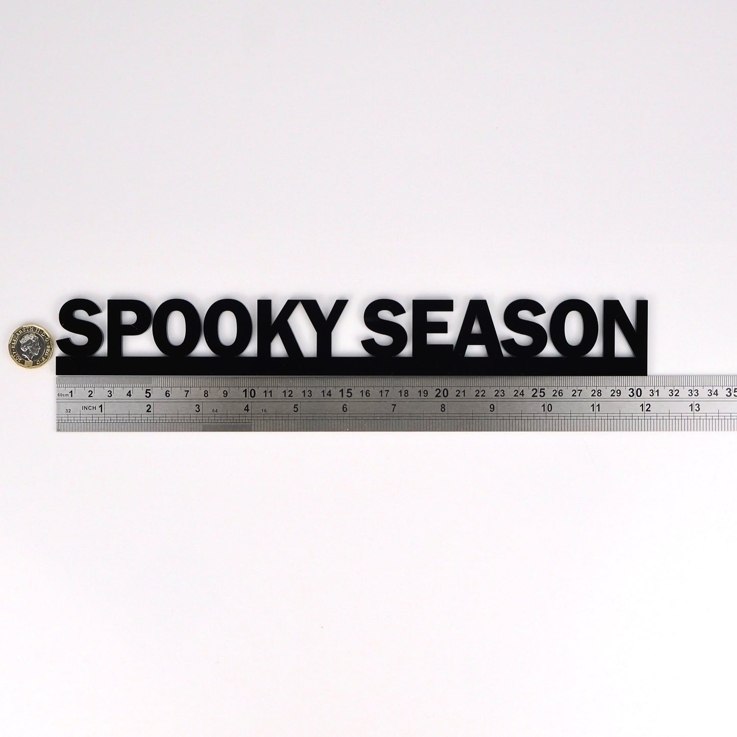 SPOOKY SEASON wall sign beside a pound coin for size reference