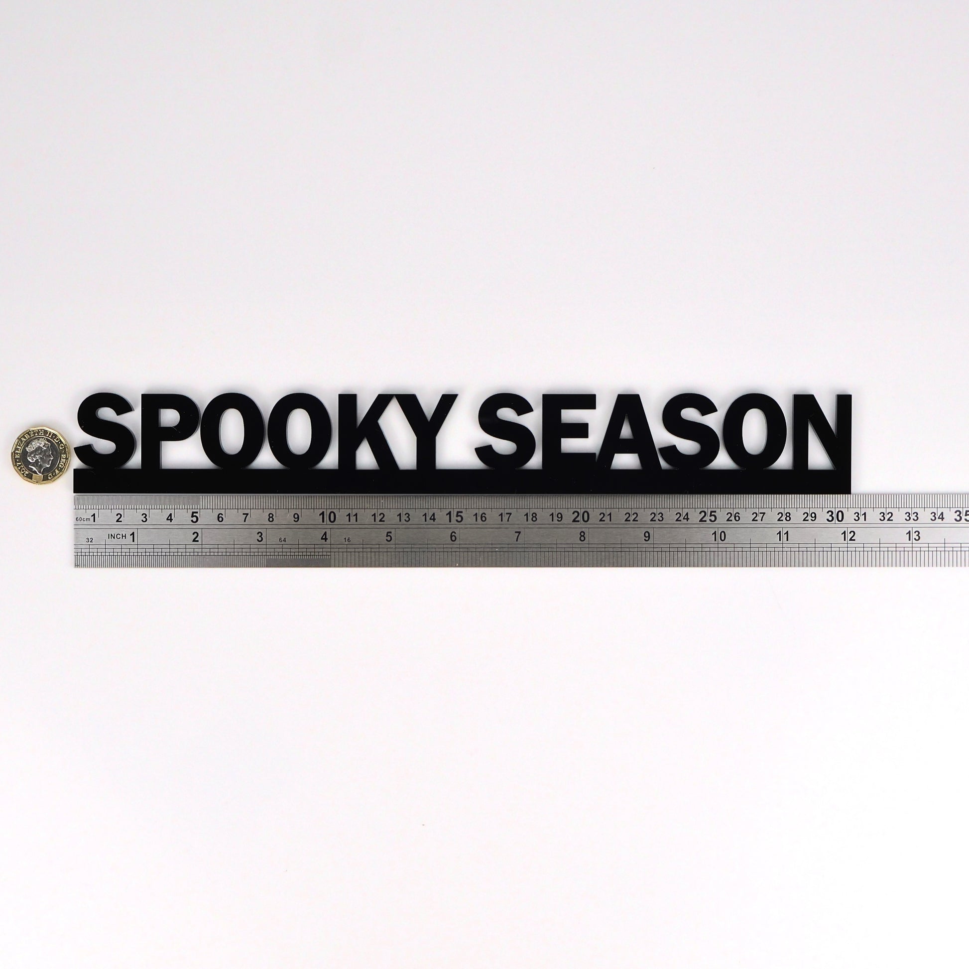 SPOOKY SEASON wall sign beside a pound coin for size reference