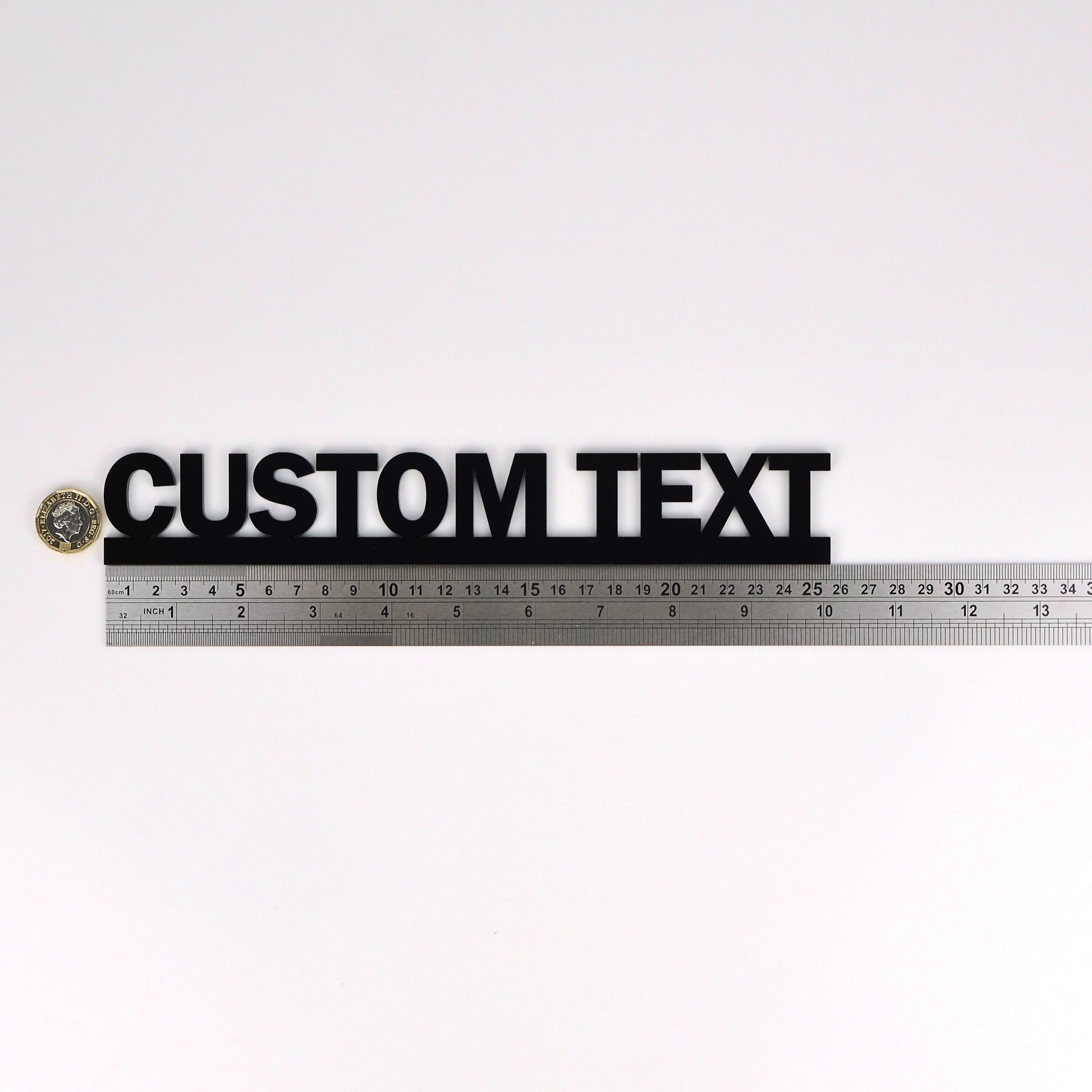 Flat-lay showing custom text door topper beside ruler and pound coin for scale – compact handmade personalised decor gift made in the UK