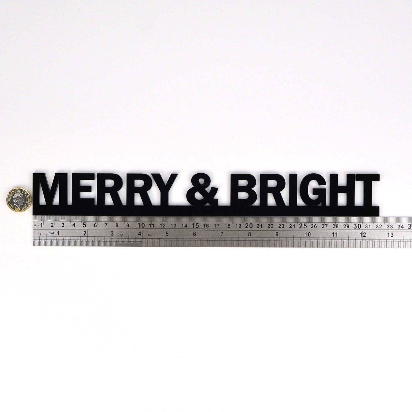 MERRY & BRIGHT sign beside a ruler and pound coin for size scale