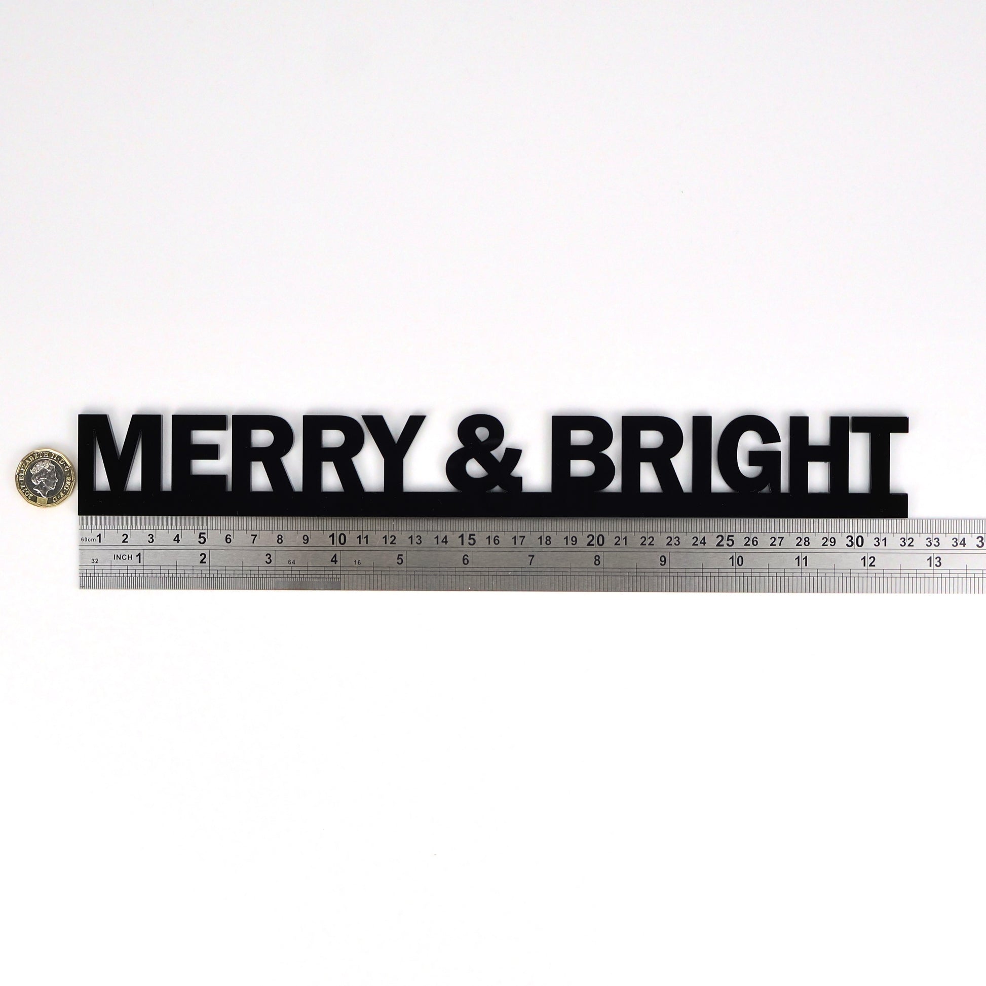 MERRY & BRIGHT sign beside a ruler and pound coin for size scale