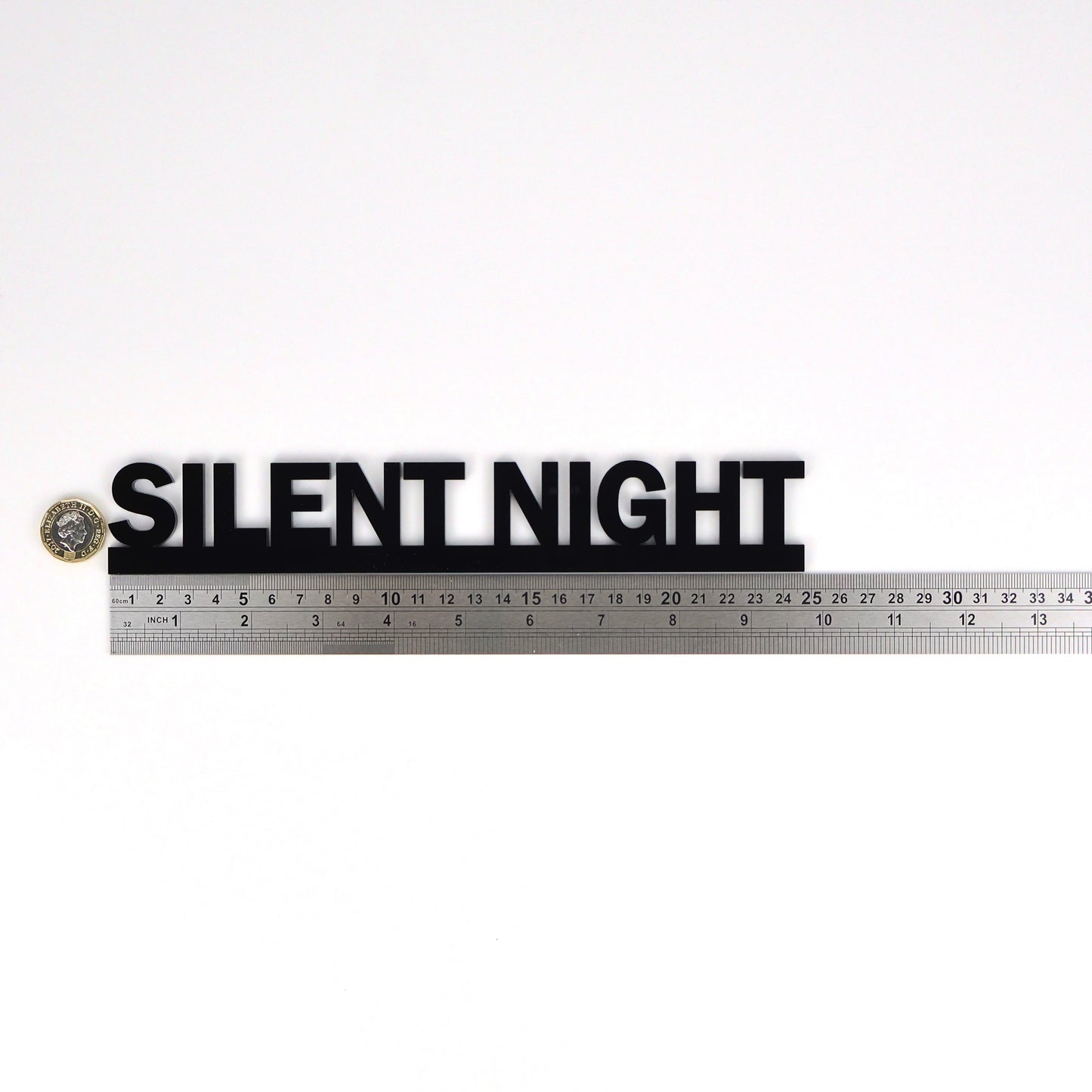 Black acrylic SILENT NIGHT Door Topper shown beside a ruler and pound coin for scale