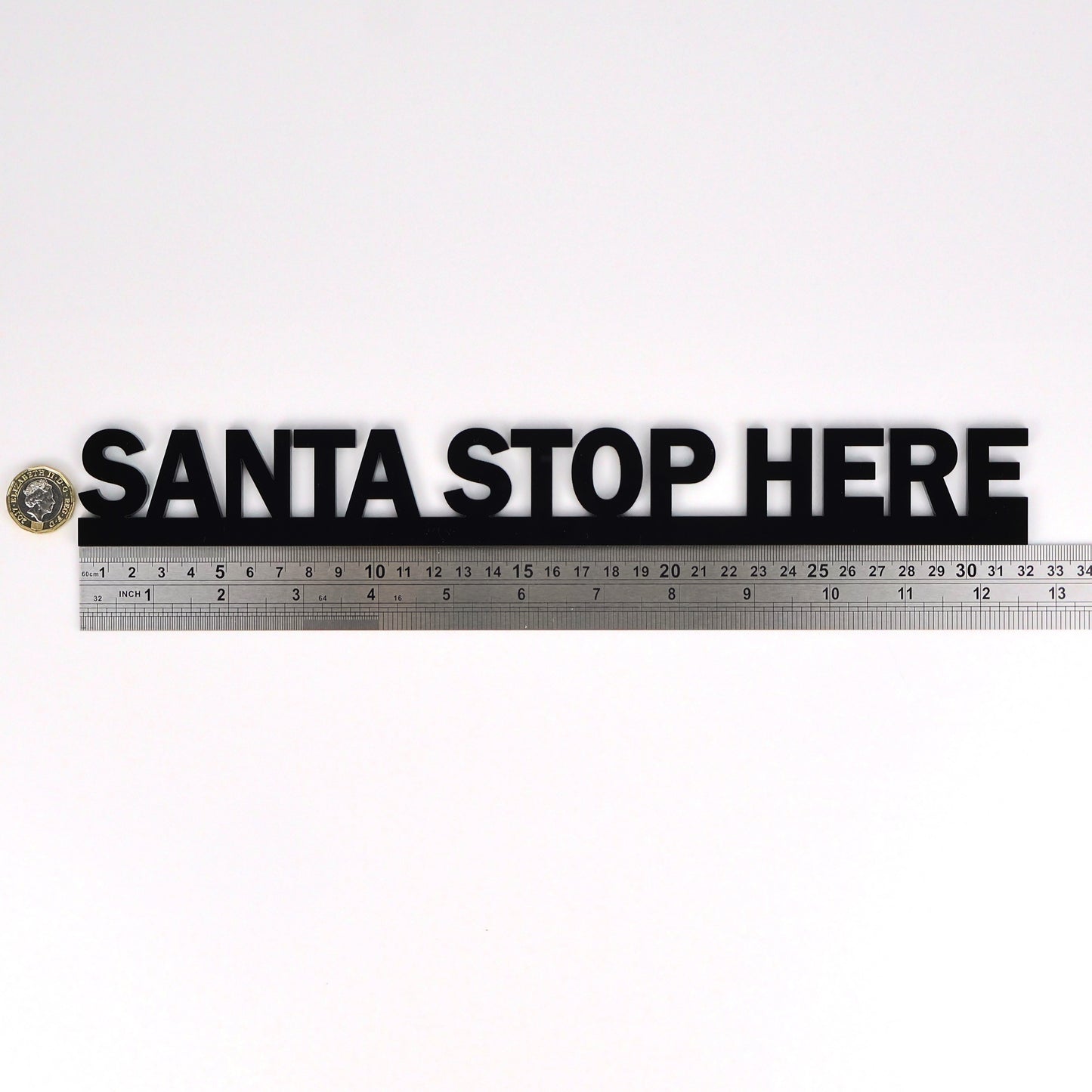 Flat lay of SANTA STOP HERE Door Topper beside ruler and pound coin for scale