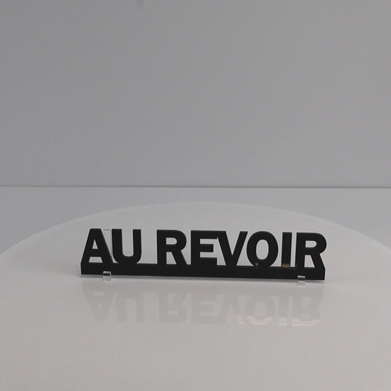 Rotating close-up video highlighting the smooth gloss finish of the AU REVOIR sign.